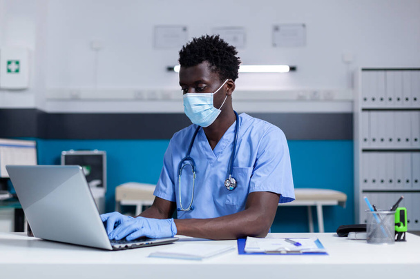 Μαύρος ενήλικας με νοσηλευτικό επάγγελμα που εργάζεται σε κλινική υγείας - Φωτογραφία, εικόνα
