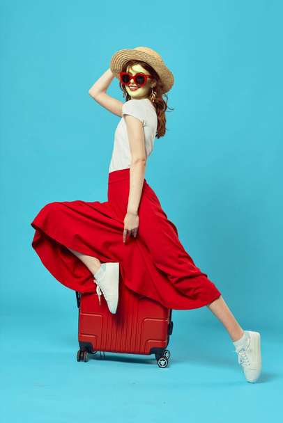 Una mujer sentada en una maleta roja. Foto de alta calidad - Foto, imagen