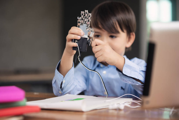 Детская самоизоляция с помощью планшета для его домашней работы, ребенок играет с роботизированной рукой в одиночку во время covid 19 блокировать, домашнее обучение, социальное расстояние, электронное обучение онлайн образование. - Фото, изображение