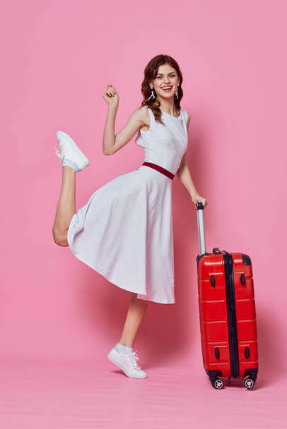 piros bőröndös nő rózsaszín háttérrel. Kiváló minőségű fénykép - Fotó, kép