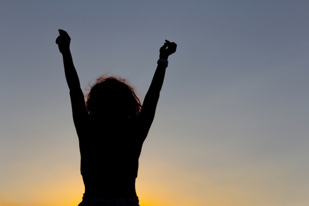 Kobieta z rękami podniesionymi o zachodzie słońca. Uczucie szczęścia i zwycięstwa. Przestrzeń kopiowania. - Zdjęcie, obraz