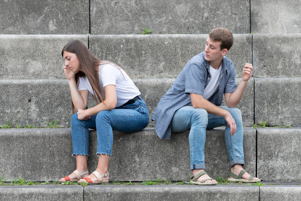 Suhteen ongelmat käsite. Surullinen pari istuu portaissa välittämättä toisistaan. Ristiriita miehen ja naisen välillä. - Valokuva, kuva