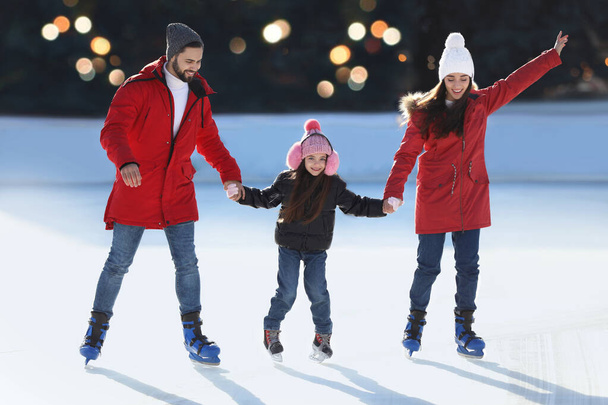 Happy family spending time together at outdoor ice skating rink - Photo, image