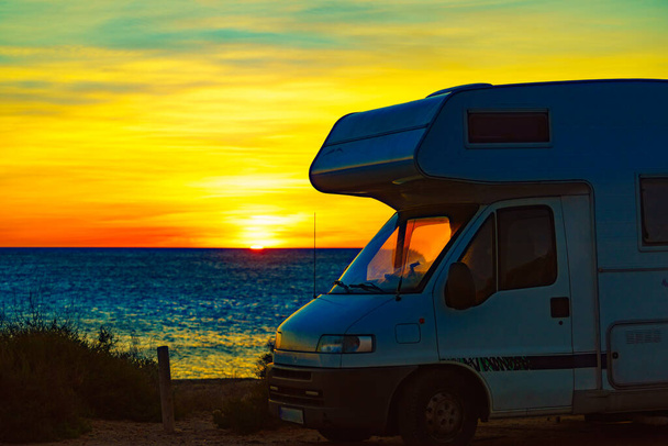 Caravan recreational vehicle at sunrise on mediterranean coast in Spain. Camping on nature beach. Vacation and travel in motor home. - Foto, afbeelding