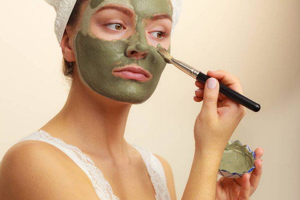 Skin care. Woman applying with brush clay mud mask to her face. Girl taking care of oily complexion. Beauty treatment. - Foto, imagen