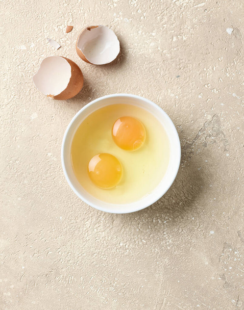 bowl of raw eggs on beige color kitchen table, top view - Valokuva, kuva