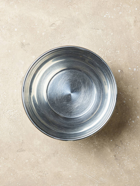 cuenco de metal vacío en una mesa de cocina de color beige, vista superior - Foto, Imagen