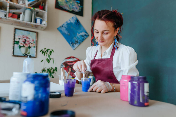 Artista femminile versando mezzo acrilico per dipingere quadro in tecnica fluida versando - Foto, immagini
