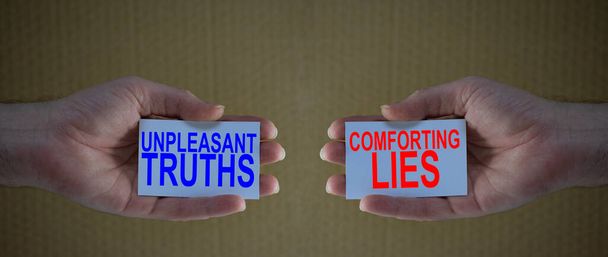 unpleasant truths versus conforting lies on cardboards in man's hands, Concept for different choices in life, people preferring conforting lies above unpleasant truths - Photo, Image