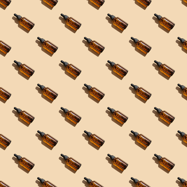 Pattern of mock-ups of glass dropper bottles with hard shadows of sunlight on isolated beige background. Concept of beauty industry - Φωτογραφία, εικόνα