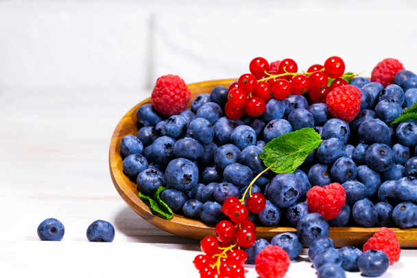 Blueberries With a Green Mint leaf in a Wooden Bowl on a white top view, Summer Freshly Berry, Copyspace. - Foto, immagini