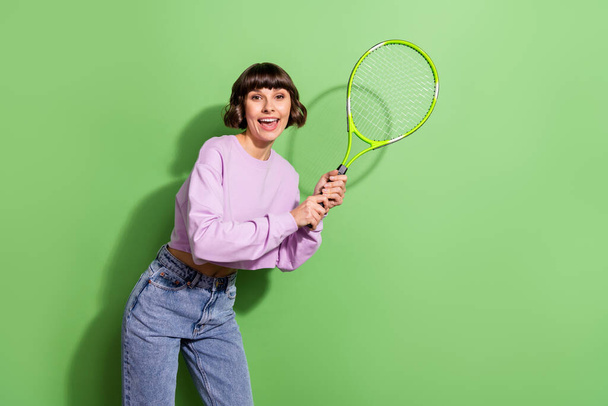 Portrait of attractive cheerful girl playing badminton spending weekend isolated over bright green color background - Zdjęcie, obraz