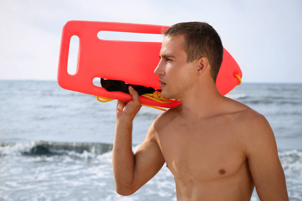 Handsome lifeguard with life buoy near sea - 写真・画像