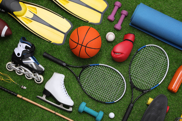 Different sport equipment on green grass, flat lay - Fotó, kép
