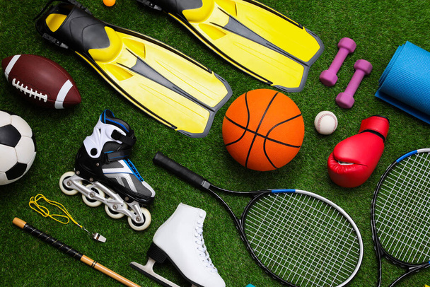 Different sport equipment on green grass, flat lay - Zdjęcie, obraz