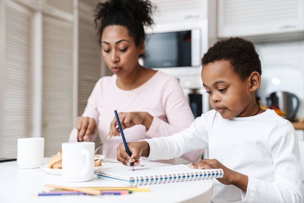 Black boy drawing while having breakfast with her mother at home - Φωτογραφία, εικόνα