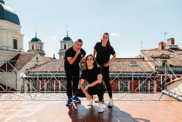 Fitnessgeräte von drei jungen Frauen auf einer Terrasse, die in die Kamera schauen - Foto, Bild