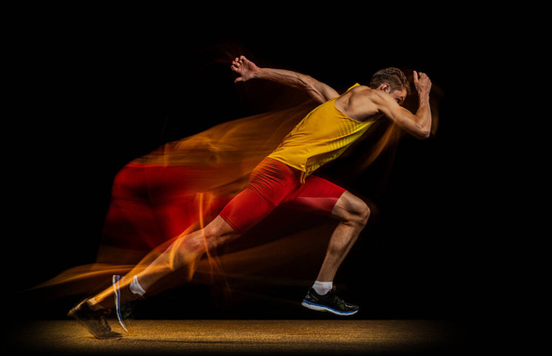 Portrait of young man, professional male athlete, runner in motion and action isolated on dark background. Stroboscope effect. - Fotografie, Obrázek