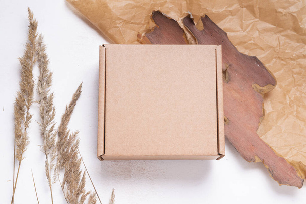 Brown flat cardboard carton box decorated with dried leaves, top - Fotó, kép