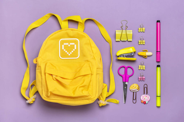 Back to school, education concept. Yellow backpack with school supplies - notebook, pens, ruler, calculator, scissors isolated on purple background Top view Copy space Flat lay composition Banner. - Photo, Image