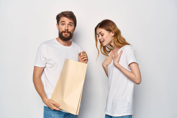 молода пара в білих футболках паперовий мішок продажу покупки
 - Фото, зображення
