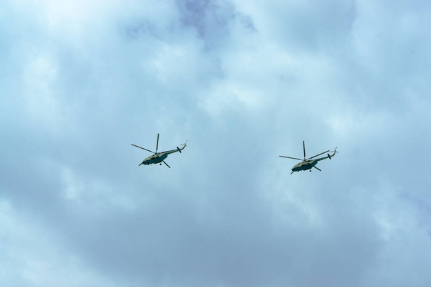 militaire helikopters vliegen hoog in een blauwe bewolkte lucht - Foto, afbeelding