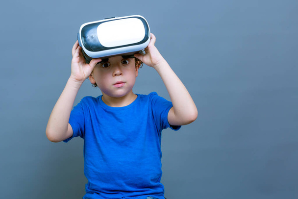 small boy holding up his virtual reality goggles with an astonished expression - Foto, imagen