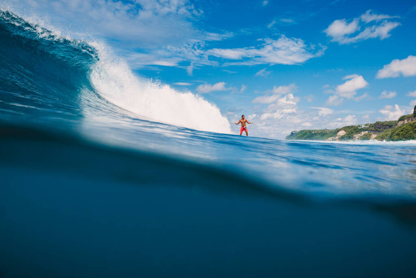 04 aprile 2021. Bali, Indonesia. Surfer cavalcata maschile su tavola da surf a onda blu oceano. - Foto, immagini