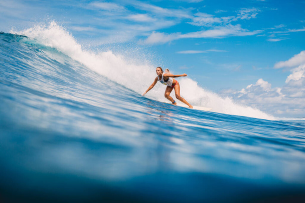 04 апреля 2021 года. Бали, Индонезия. Спортивная девушка в тропическом океане во время серфинга. Девушка-серфер на доске для серфинга и идеальная океанская волна.  - Фото, изображение