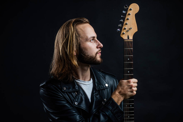 bearded rock musician with electric guitar neck in leather jacket, music - Fotoğraf, Görsel