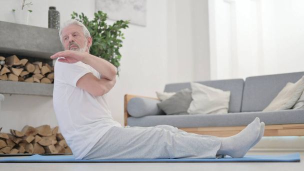 Alter Mann macht Stretches auf Trainingsmatte zu Hause - Foto, Bild