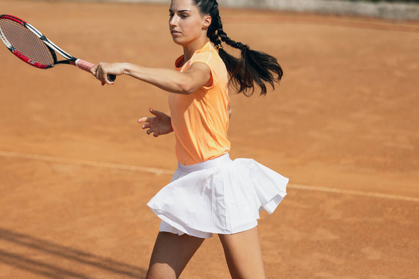 Yksi kaunis nuori urheilija, tennispelaaja mailalla harjoitellaan savea tenniskenttä kesäpäivänä. - Valokuva, kuva