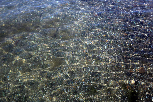Reflectie van de zonnestralen in het water, de bodem is zichtbaarHet oppervlak van het water wordt doorboord door de zonnestralenDe textuur van de bodem - Foto, afbeelding