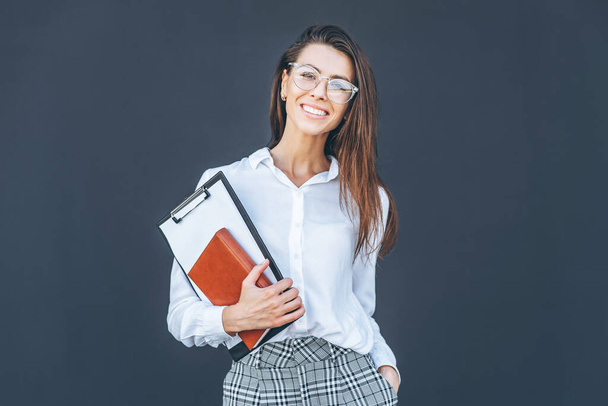 Young business woman with coffee and notebook on grey background - Φωτογραφία, εικόνα