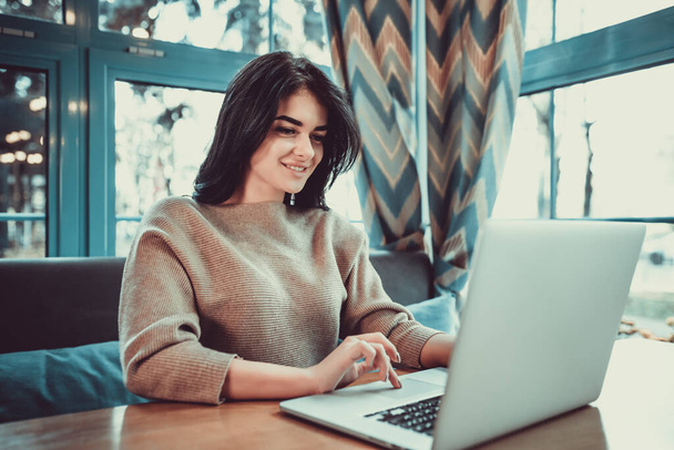 La femme heureuse avec un ordinateur portable s'assoit dans un café - Photo, image