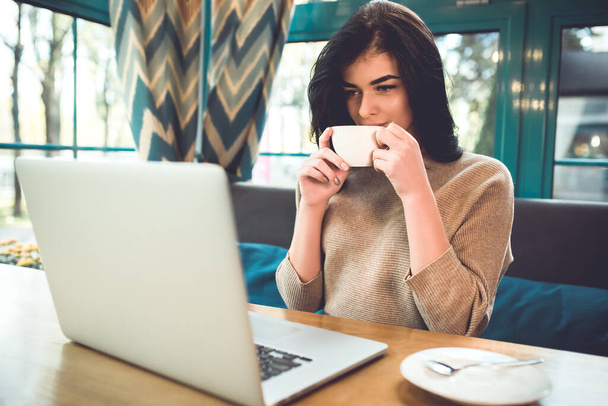 Houkutteleva nainen läppäri juoda kahvia kahvilassa - Valokuva, kuva