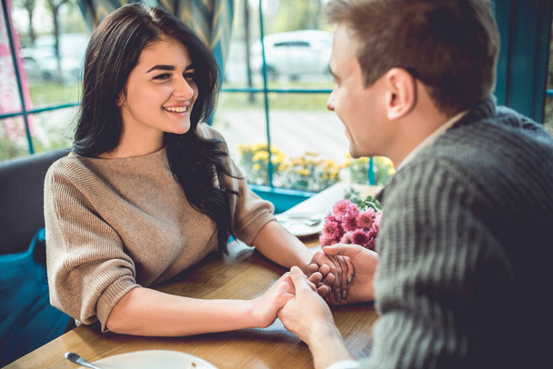 Das glückliche Paar sitzt im Café und hält Händchen - Foto, Bild