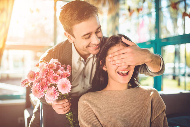 Щасливий чоловік робить сюрприз з квітами для дівчини в ресторані
 - Фото, зображення