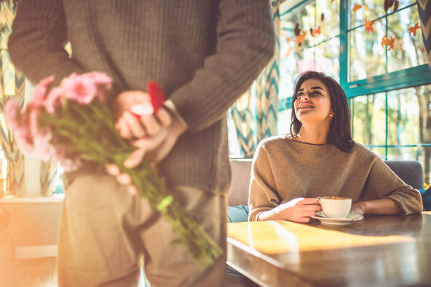 Der Mann mit den Blumen macht seiner Frau im Restaurant einen Heiratsantrag - Foto, Bild