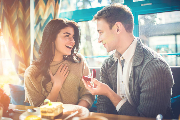 Szczęśliwy mężczyzna oświadcza się swojej kobiecie w restauracji. - Zdjęcie, obraz
