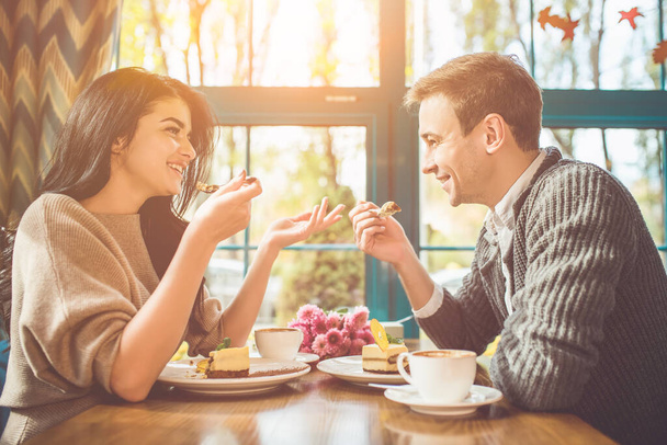 Счастливые мужчина и женщина едят торт в кафе - Фото, изображение