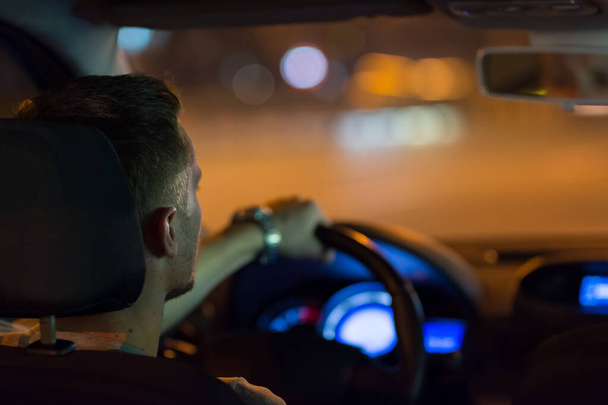 Чоловік водить машину в нічному місті
 - Фото, зображення