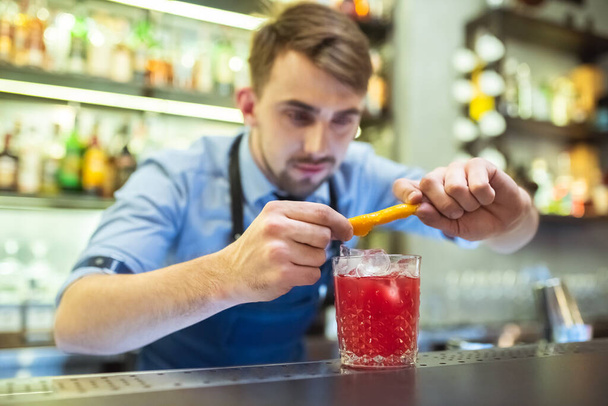 The barman making a red cocktail with an orange on the bar - Foto, immagini
