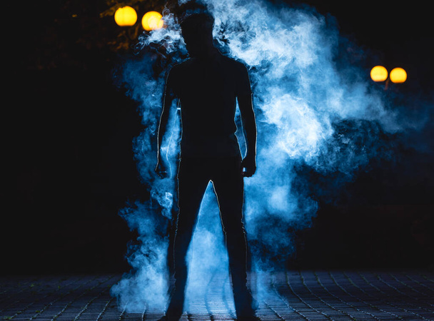The man stand on the blue smoke background. night time - Photo, Image
