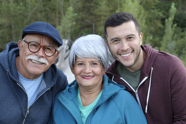 grupowy portret szczęśliwej rodziny z parą seniorów i ich młodym synem w parku - Zdjęcie, obraz