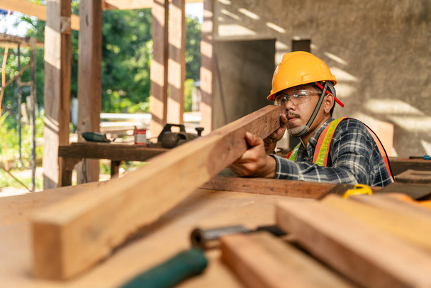 Asijský tesař vizuálně kontroluje přesnost dřeva na staveništi. - Fotografie, Obrázek