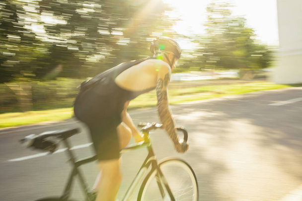 Joven ciclista masculino montando una bicicleta de carretera en el día de verano. Acción, concepto de movimiento - Foto, imagen