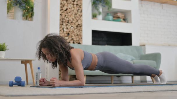 Young African Woman doing Plank on Excercise Mat at home - Photo, Image