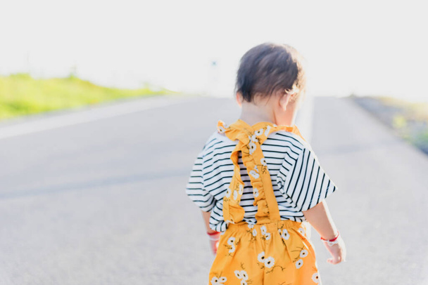 コピースペースで牧草地を歩くアジアの赤ちゃんの女の子のクローズアップ幸せな家族の日のコンセプト。シルエット. - 写真・画像