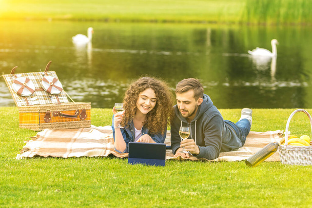 El hombre y la mujer beben un vino cerca del río - Foto, imagen